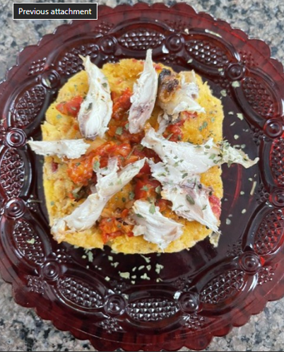 Puerto Rican Mofongo served on a decorative red plate topped with shredded chicken and tomato sauce